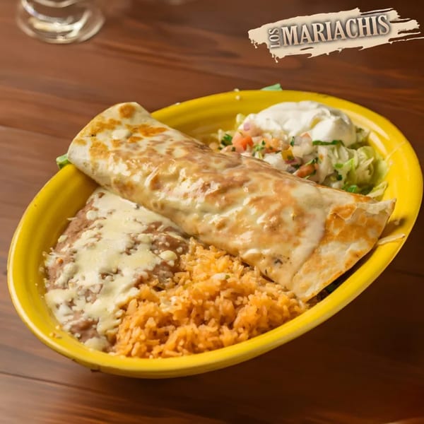 A Los Mariachis burrito with melted cheese, rice, refried beans, and a side salad with sour cream.