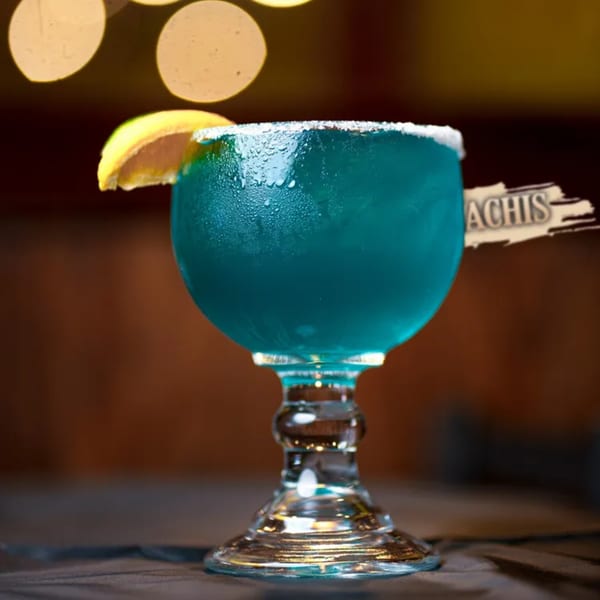 A vibrant blue margarita with a salted rim and lime wedge, branded with "Los Mariachis".