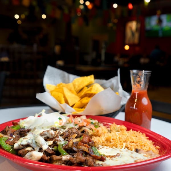 Los Mariachis' sizzling fajitas with rice, beans, and tortillas, alongside chips and salsa.